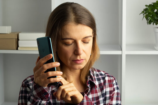 Woman using her smart phone with her eyes closed